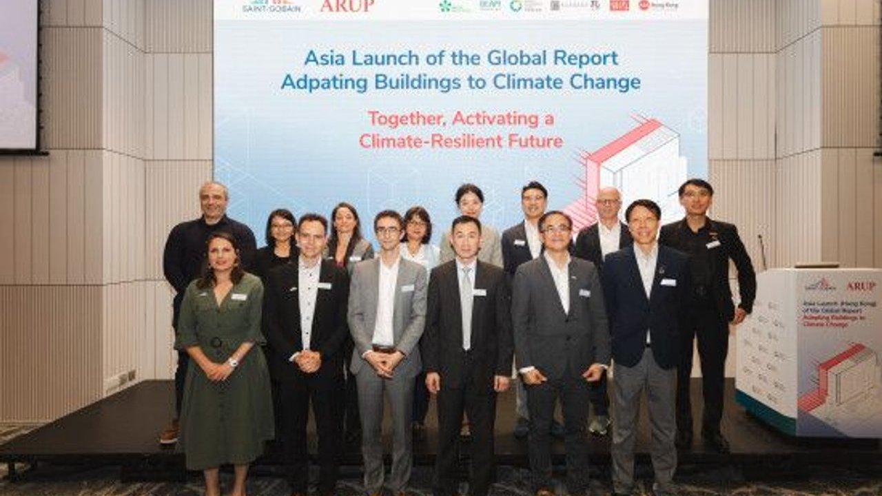 Group of event attendees standing before a screen for a climate-resilient buildings report launch.