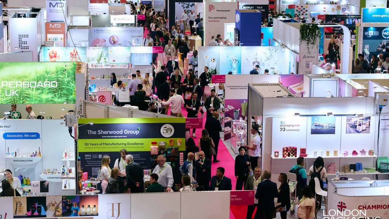 Crowded packaging trade show floor with exhibition booths and attendees.
