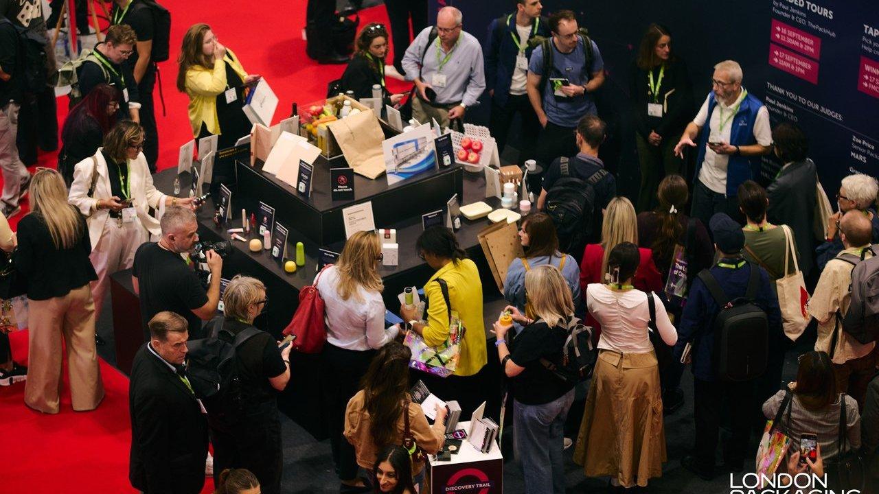 Crowd gathered around a cosmetics display booth at a trade show.