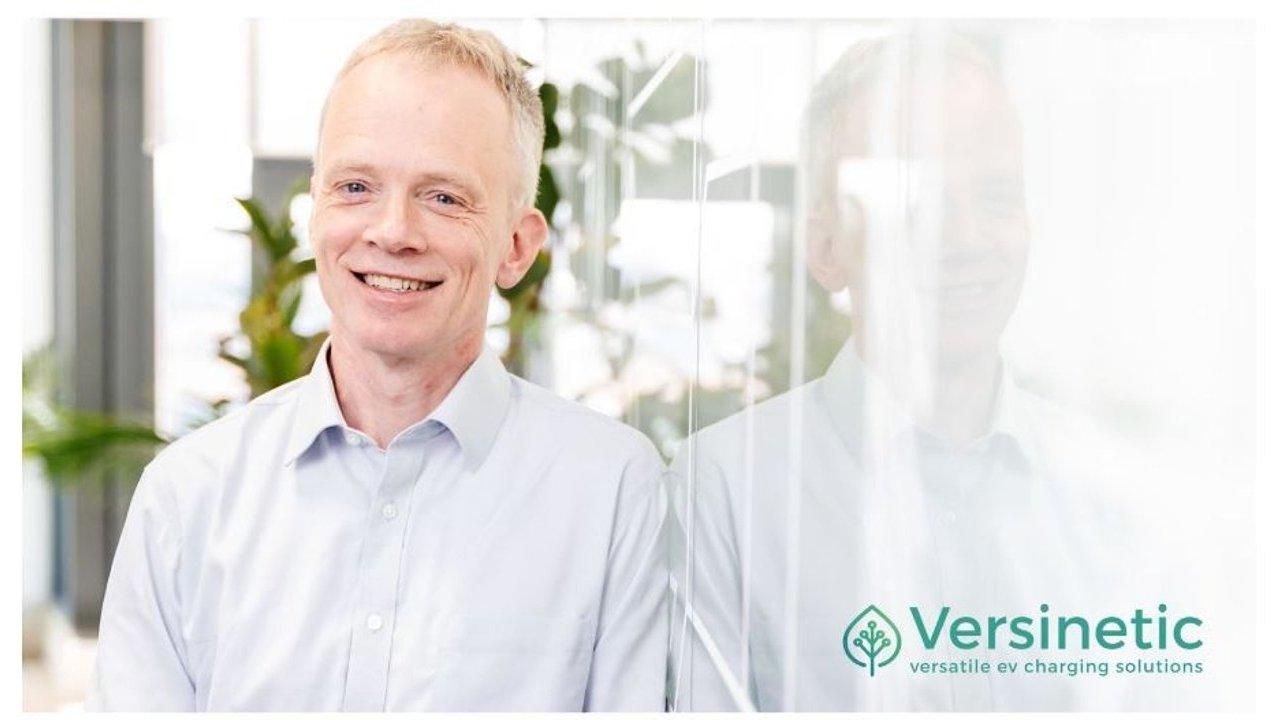 Dunstan Power, Director of Versinetic, smiling in an office beside a glass reflection.
