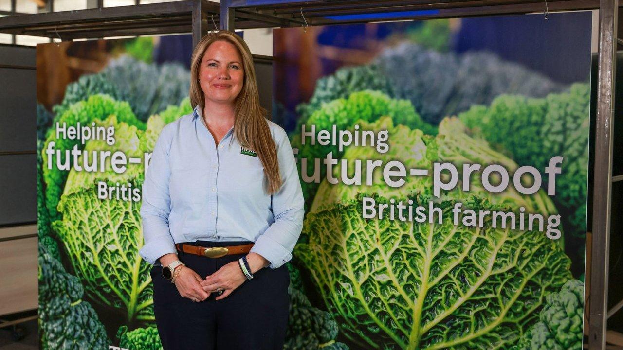 Jilly Grant stands before a display reading “Helping future-proof British farming,” with images of leafy greens.