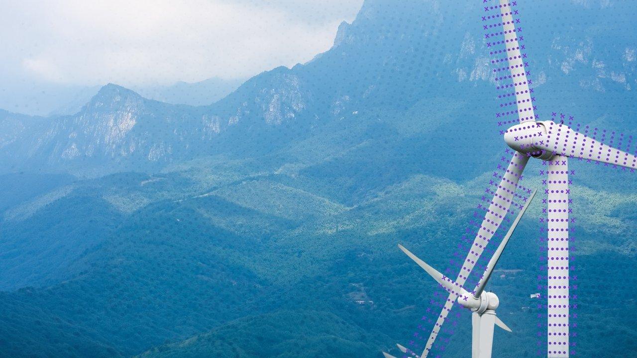 Wind turbines with purple dot patterns overlooking forested mountains.