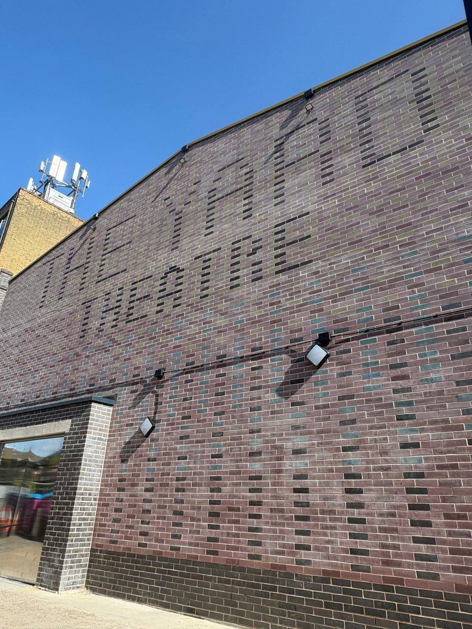 Dark brick facade of the Yard Theatre with its name spelled in recessed bricks.