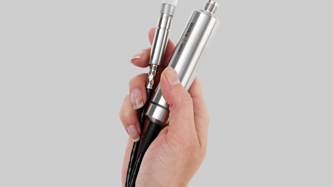 A hand holding a Vaisala HMP7 humidity and temperature probe and cable.