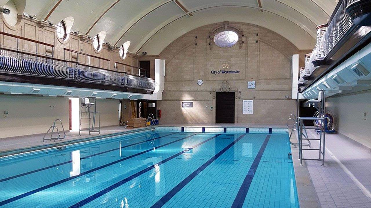 Indoor swimming pool with lane markings, diving boards and balconies at Porchester Leisure Centre.