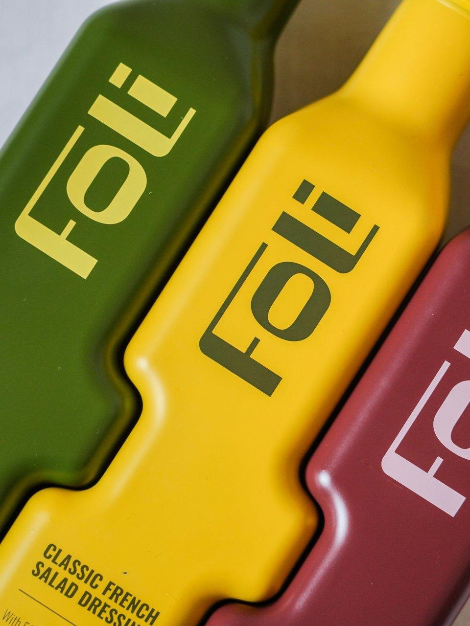 Green, yellow and red bottles of Oli salad dressing, with “Classic French Salad Dressing” on the yellow bottle