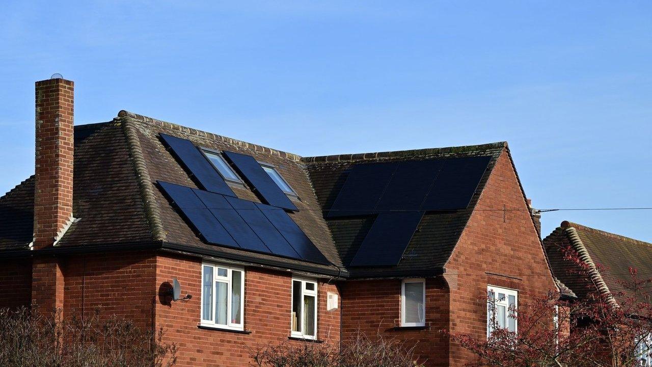 Solar panels on the roof of a red brick house under a clear blue sky