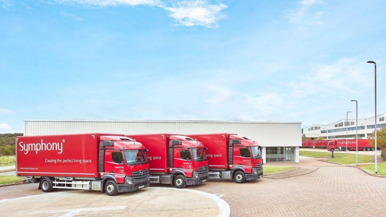 Three red delivery trucks parked outside a warehouse.