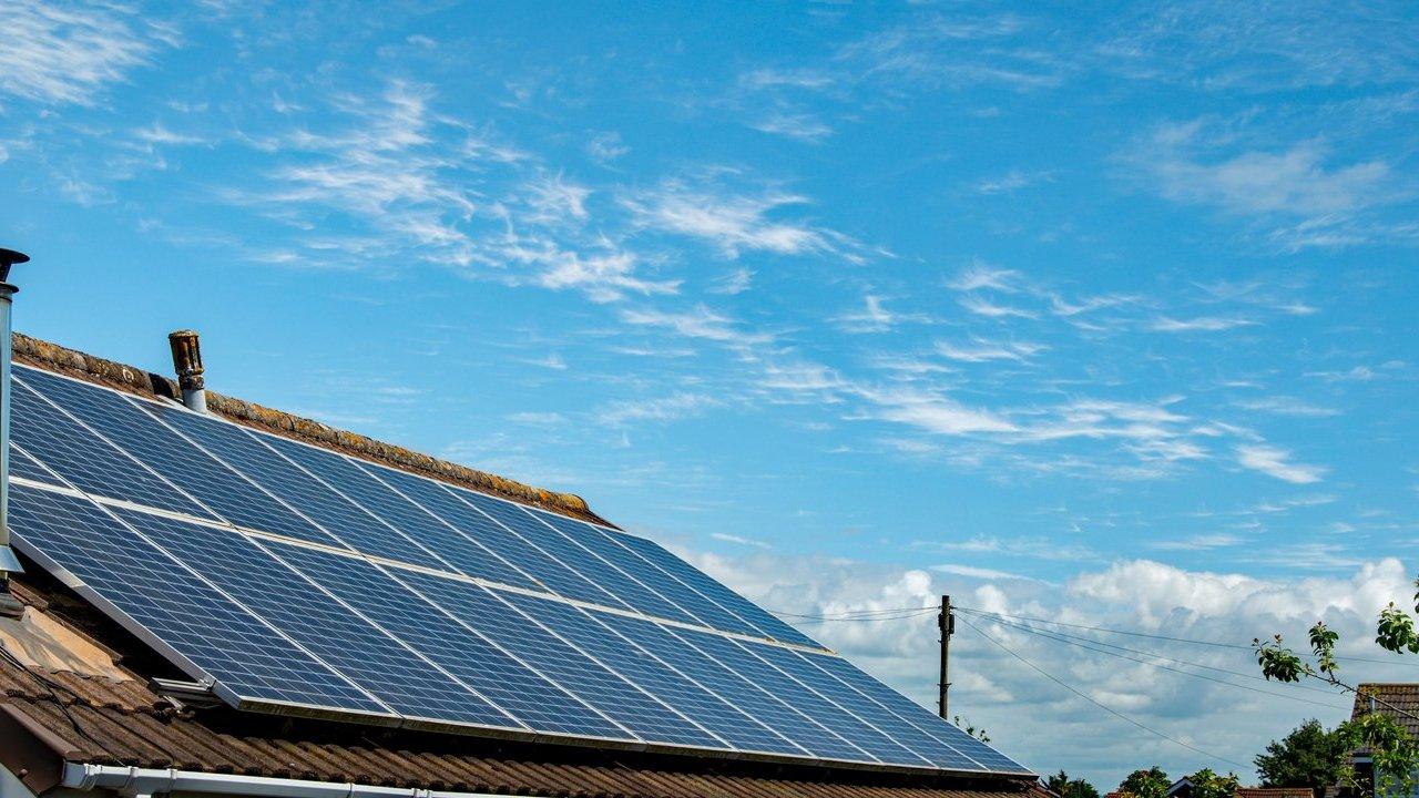 Solar panels installed on the roof of a house beneath a blue sky.
