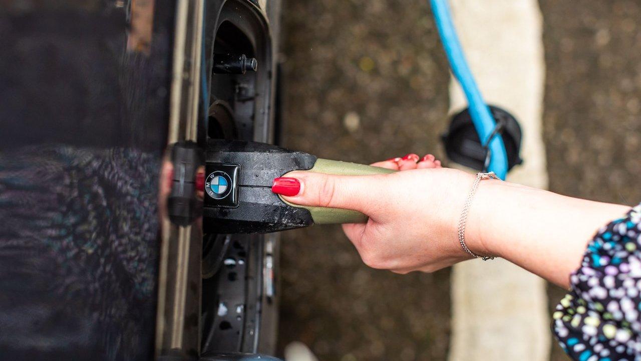 A person plugs a charging cable into a BMW electric car.