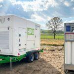 Hydrogen power unit on a trailer beside a bundled 300-bar gas cylinder rack in a rural field