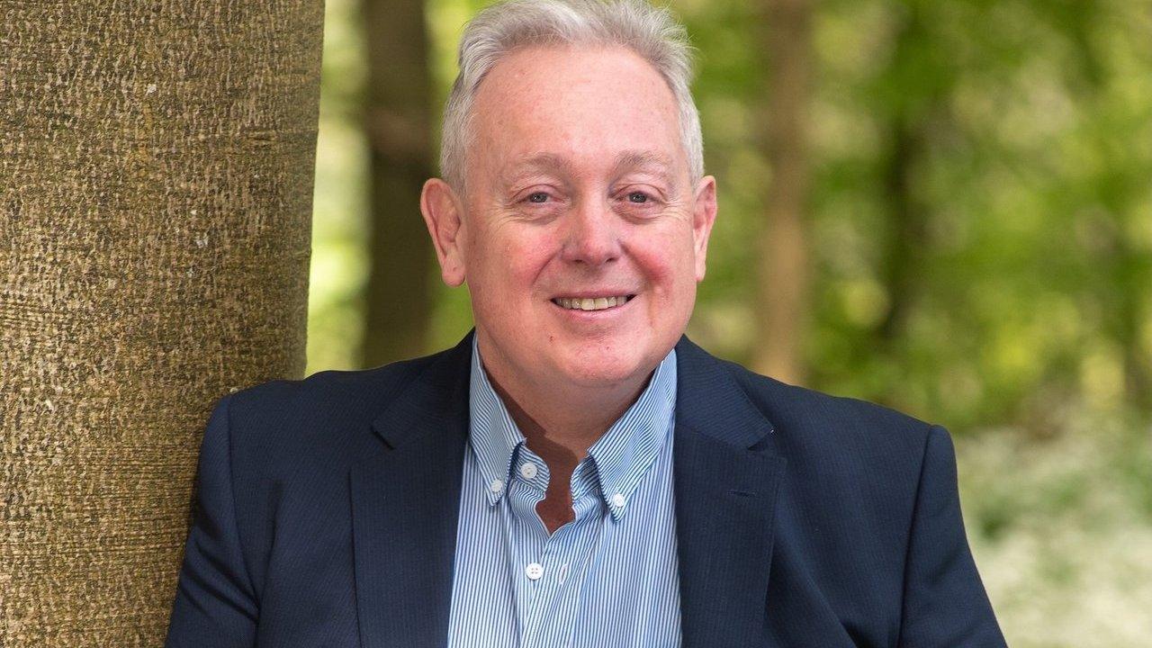 Bob Taylor in a navy jacket and striped shirt beside a tree outdoors