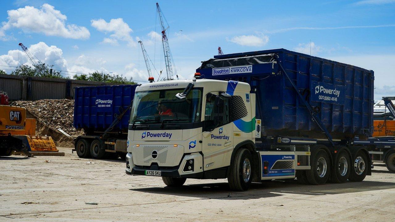 Powerday skip lorry at a construction site with rubble, excavator and cranes.