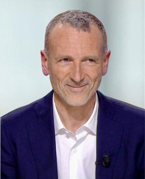 Emmanuel Faber wearing a navy suit jacket and white shirt against a pale background.