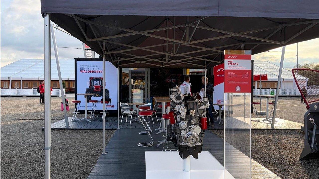 An exposed engine display beneath an FPT Interforst stand canopy with tables and chairs.