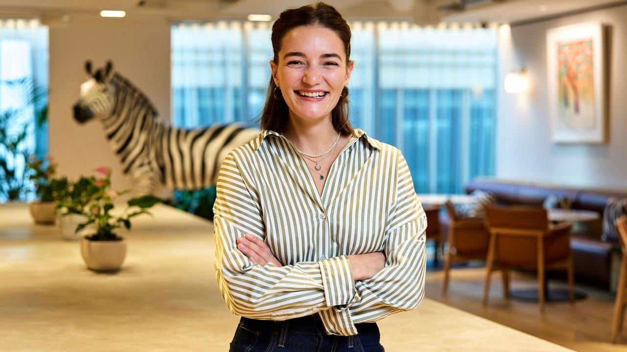 Fyona S guin stands smiling with folded arms in an office, with a zebra sculpture behind her.
