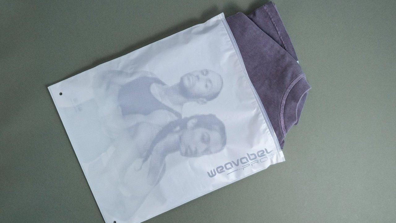 Purple underwear partially inside a white mesh laundry bag on a green surface