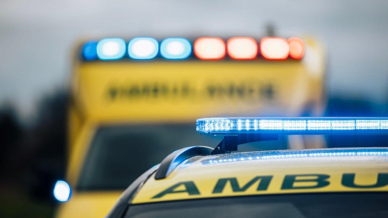 An ambulance with flashing blue lights in front of a second emergency vehicle with red and blue lights