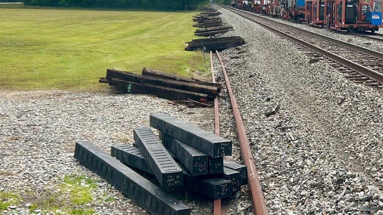 Stacks of replacement railroad ties beside a rail line and maintenance train.