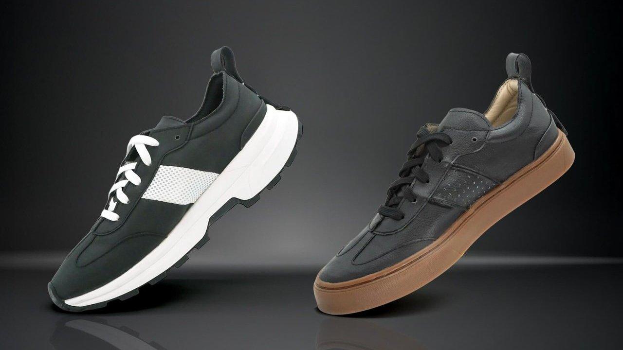 Two black footwear prototypes, one with a white sole and one with a tan sole, on a dark background.