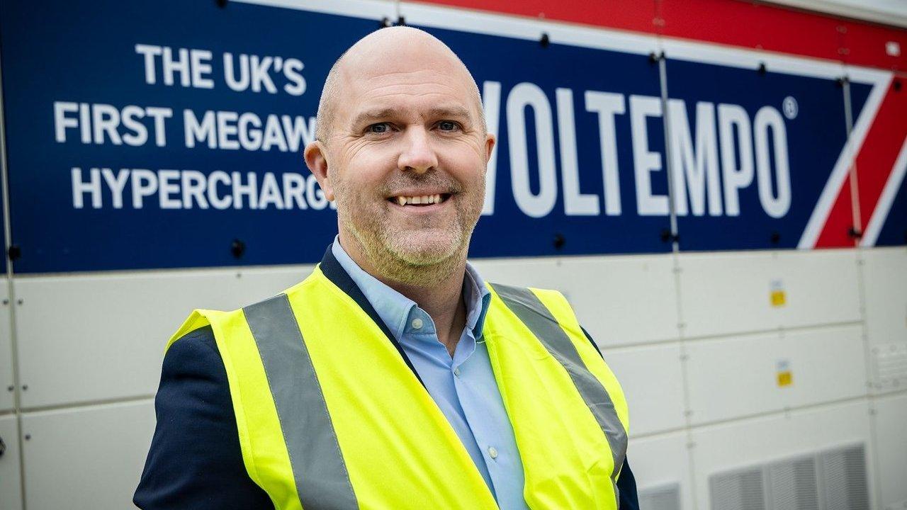 Simon Smith in a high-visibility vest standing in front of a Voltempo megawatt charger.