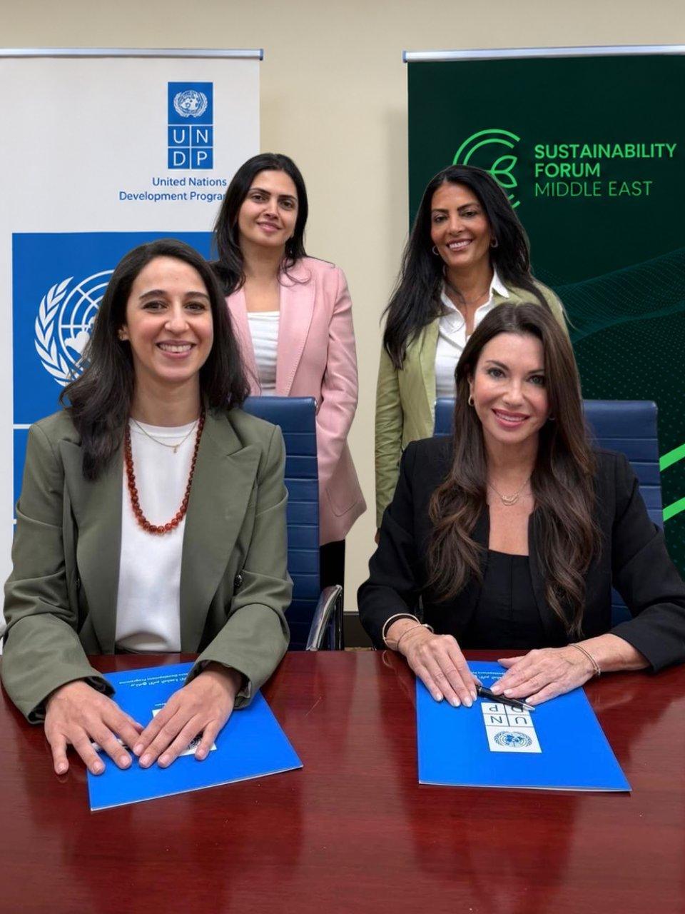 Four women at a table with UNDP folders, flanked by UNDP and Sustainability Forum Middle East banners.