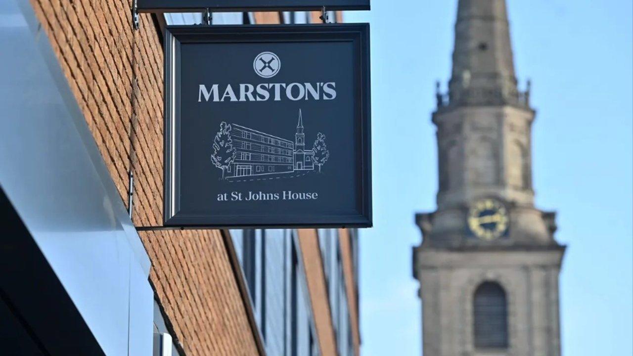 Marston’s at St Johns House sign outside a brick building, with a clock tower in the background
