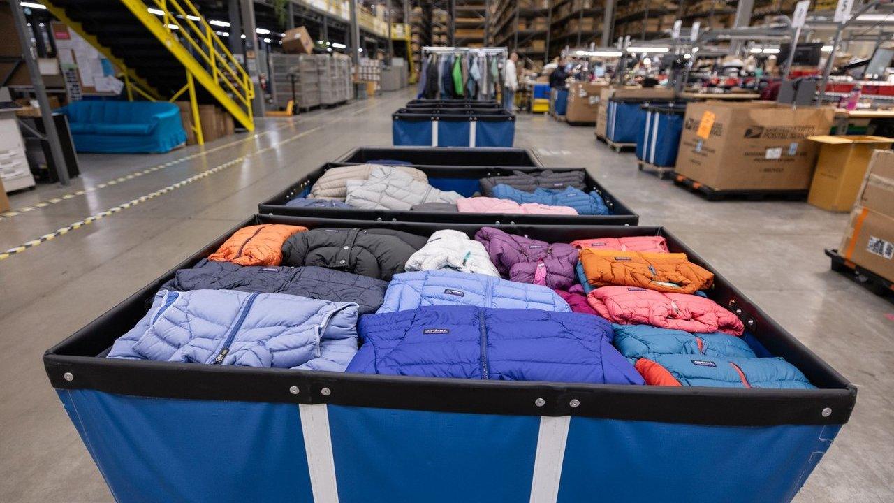 Bins filled with colorful puffer jackets in a warehouse sorting area.