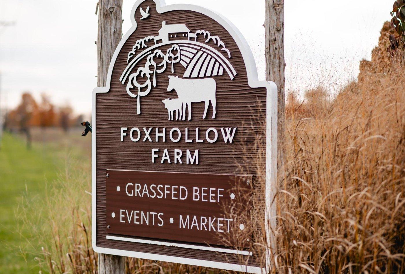 The Foxhollow Farm sign advertising grassfed beef, events and market, beside tall dry grasses