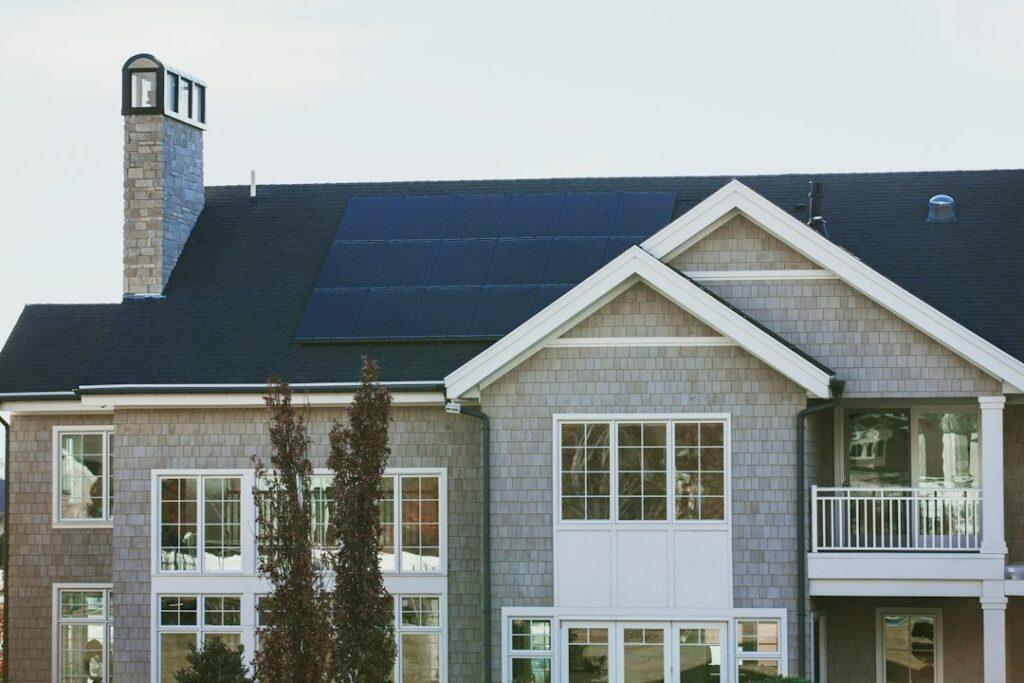 Rooftop solar panels on the dark roof of a gray shingled two-story house