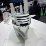 A scale model of a white industrial ship displayed at a trade show booth.
