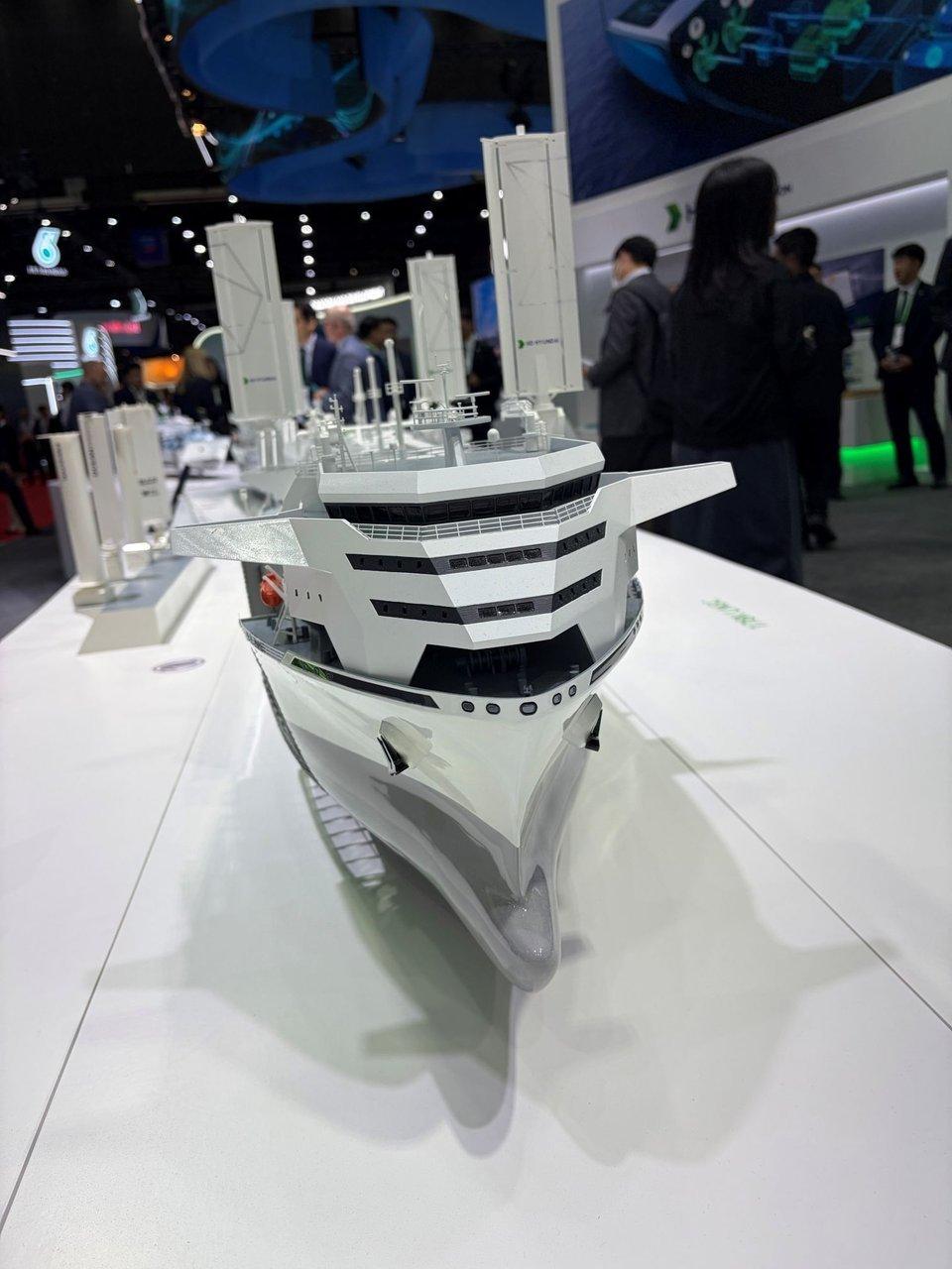 A scale model of a white industrial ship displayed at a trade show booth.