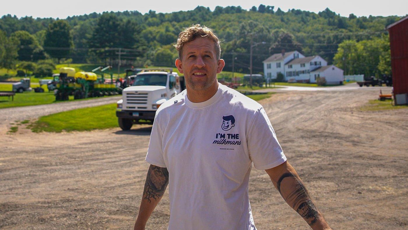 Simon Mellin, founder and CEO of Modern Milkman, in an I'm the Milkman T-shirt with a truck behind him