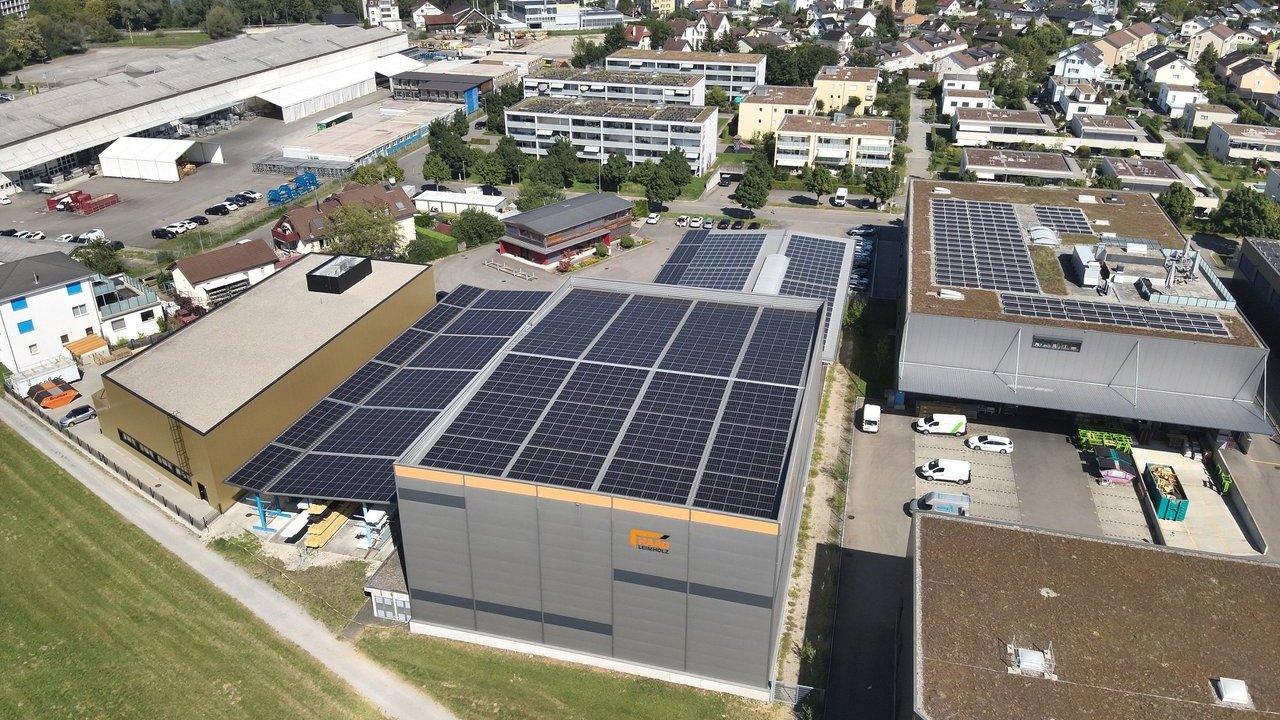 Industrial buildings with rooftop solar panels beside a residential neighborhood.