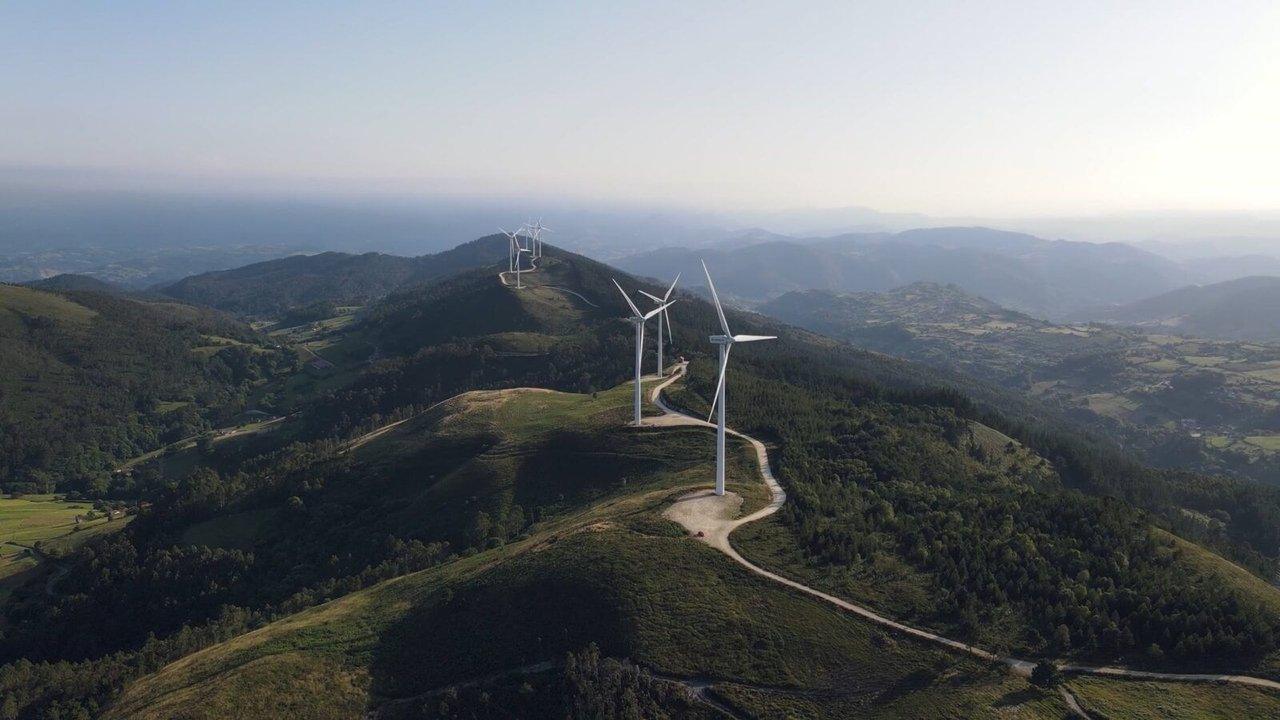 Wind turbines along a green mountain ridge with a winding access road.